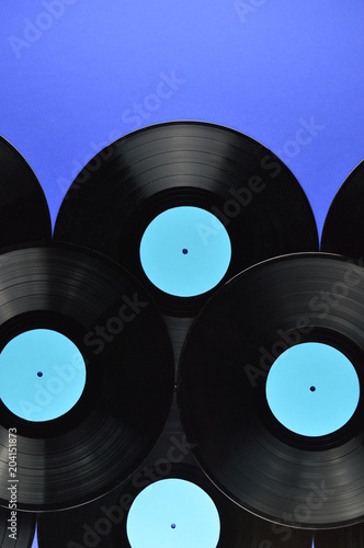 pile of old black vinyl records with blank cyan labels on blue background