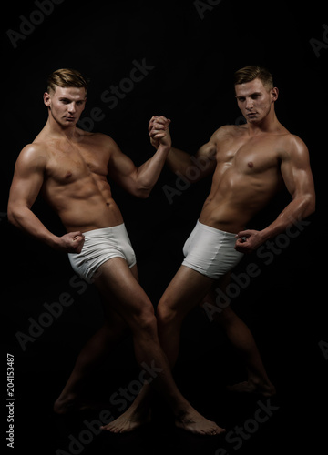 Sport workout for bodybuilder. Circus gymnasts at pilates or yoga training. Twins men with muscular body in balance pose. Fitness dieting and flexibility in acrobatics. Friendship of men do gymnastic