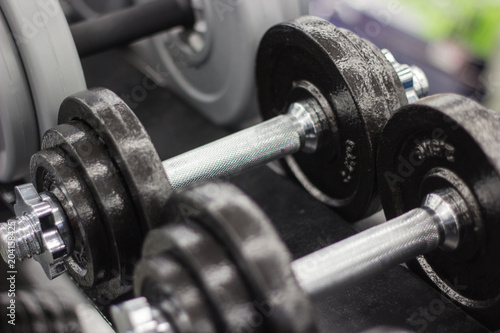 Black dumbbell set, many metal dumbbells on rack in sport fitness center