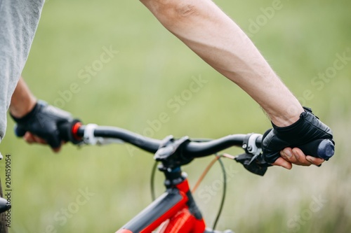 Male hands in gloves holding bicycle handlebar. Sports, tourism and activity concept
