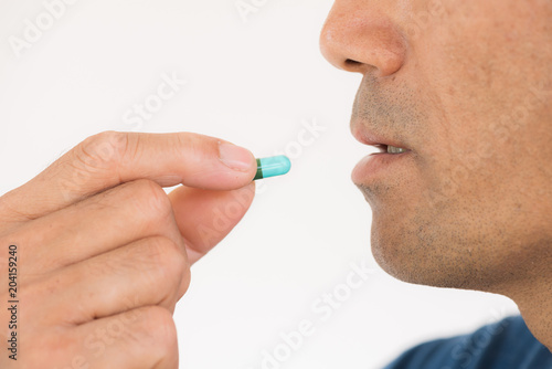medicine, health care and people concept - close up of man taking a pill.