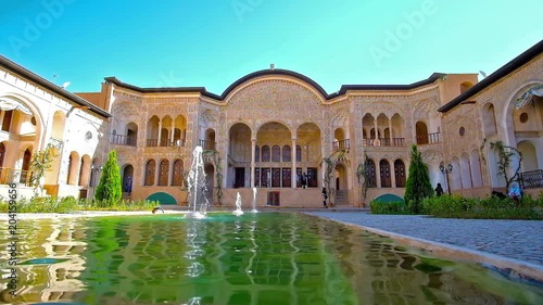 KASHAN, IRAN - OCTOBER 22, 2017: The courtyard of picturesque Tabatabaei Historical House with fountain, its main portal decorated with relief patterns and pillars, on October 22 in Kashan.  photo