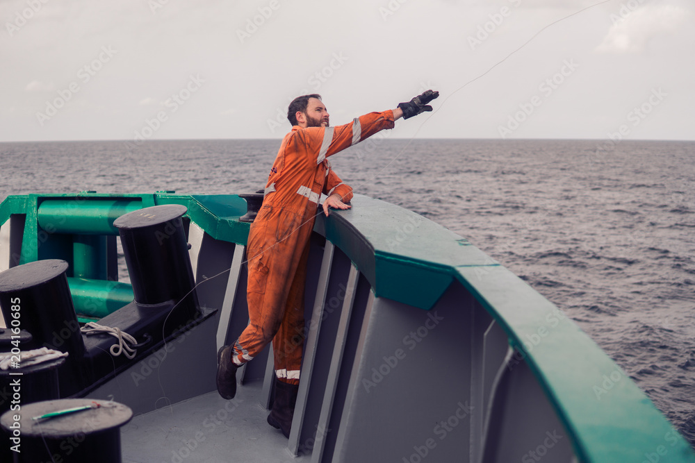 The fisherman throws a hook on a ship for catching tuna fish. Fishing at sea. He holds fishing line The fisherman throws a hook on a ship for catching tuna fish. Fishing at sea. He holds fishing line