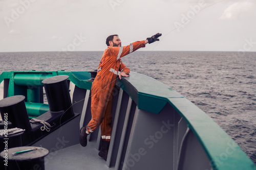 The fisherman throws a hook on a ship for catching tuna fish. Fishing at sea. He holds fishing line photo