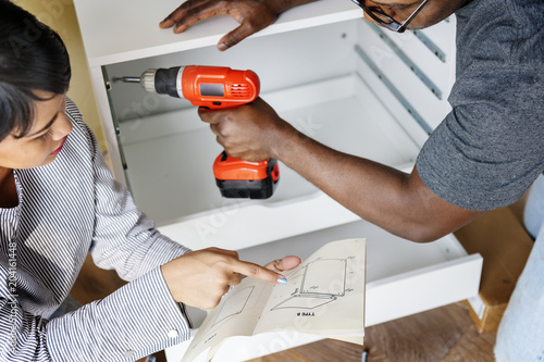 Man using electronic drill install cabinet