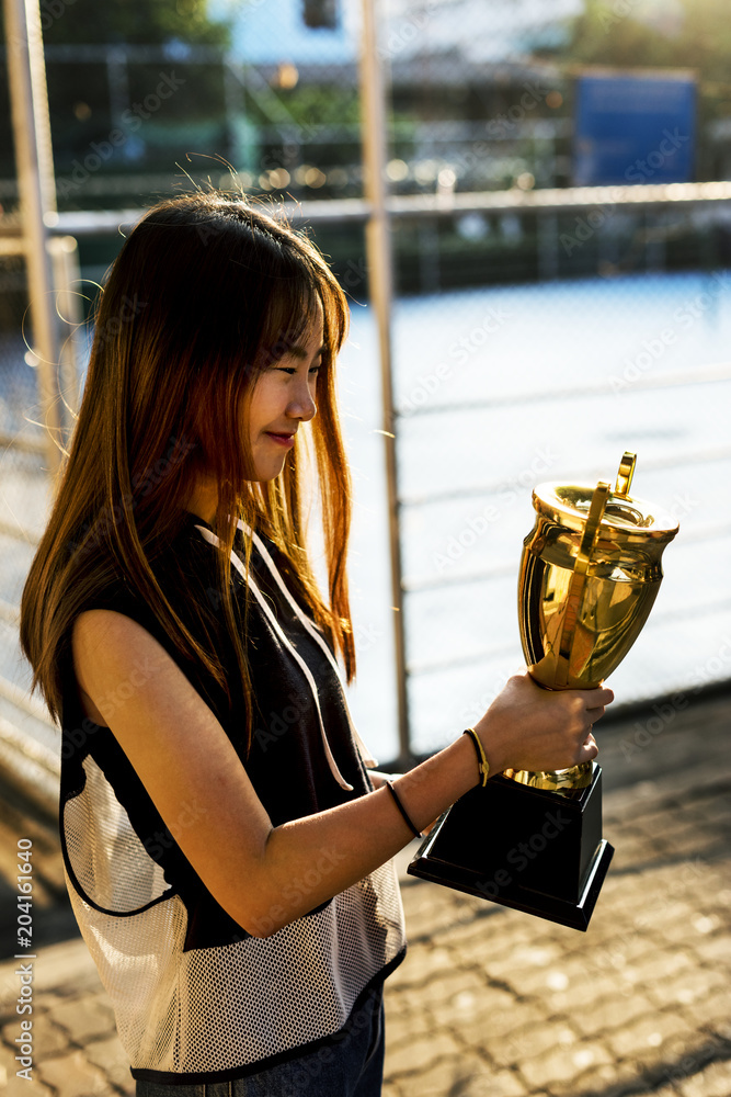Φωτογραφία Asian teenage girl in sporty clothes holding a trophy outdoors