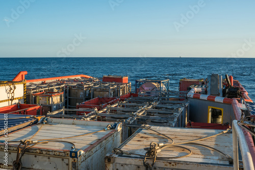 Marine cargo operations, offshore supply boat with containers and tanks onboard delivers cargo to oil rig platform. Calm sea. Dp supplier job. oil and gas research and mining indusrty photo