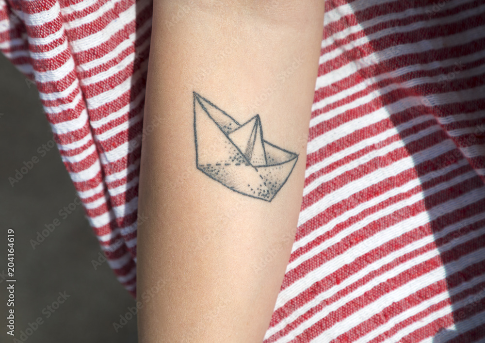 Foto Stock Barchetta di carta tatuata sul braccio | Adobe Stock