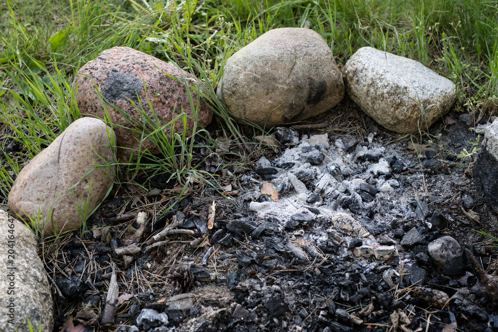 A fired fireplace by the lake. Burned pieces of wood and ash in a place for smoking fires. A fired fireplace by the lake. Burned pieces of wood and ash in a place for smoking fires.