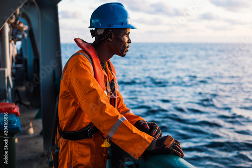 Fotografia Seaman AB or Bosun on deck of vessel or ship , wearing PPE personal protective equipment - helmet, coverall, lifejacket, goggles