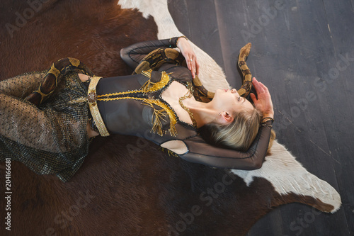 Фотография Young female dancer lying on the floor with a snake on her body