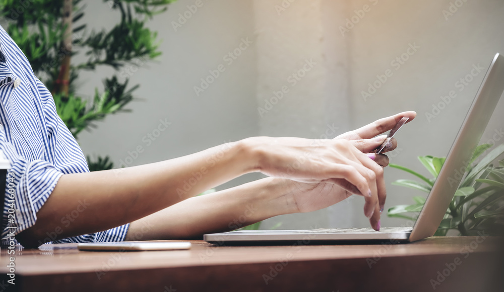 The hands of a woman holding a credit card in order to shop online. The hands of a woman holding a credit card in order to shop online.