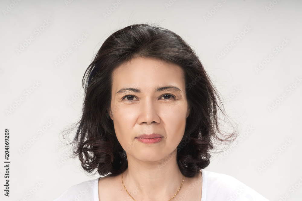 Portrait of beautiful mature asian woman with curly hair style smiling with joyful and charming on white background isolate. Close up happy and cheerful older lady wear white shirt health care concept Portrait of beautiful mature asian woman with curly hair style smiling with joyful and charming on white background isolate. Close up happy and cheerful older lady wear white shirt health care concept