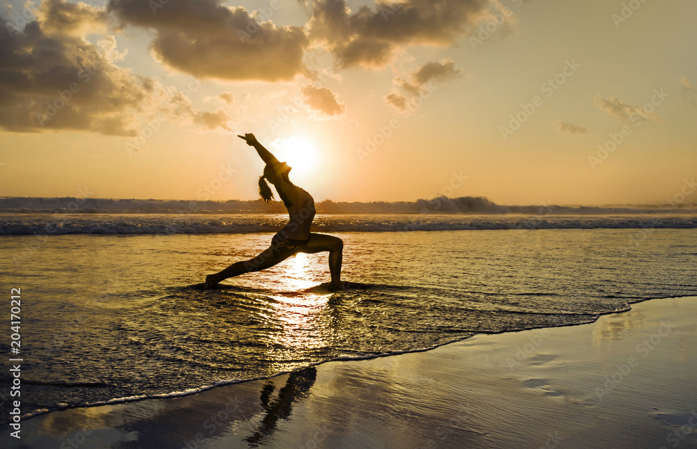 young fit and attractive sport woman in beach sunset yoga practice workout sitting on wet sun in front of the sea in meditation and relaxation exercise