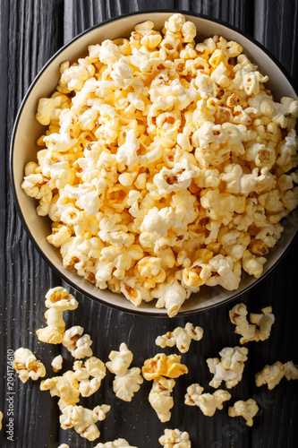 Popular snack: salted popcorn with cheddar cheese and parmesan in a bowl close-up. Vertical top view