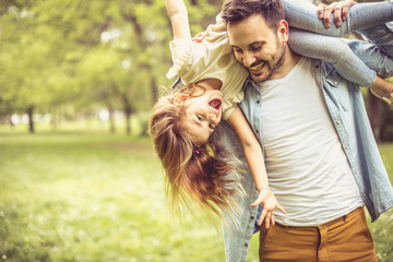 Happy father playing and carrying his daughter on shoulders.