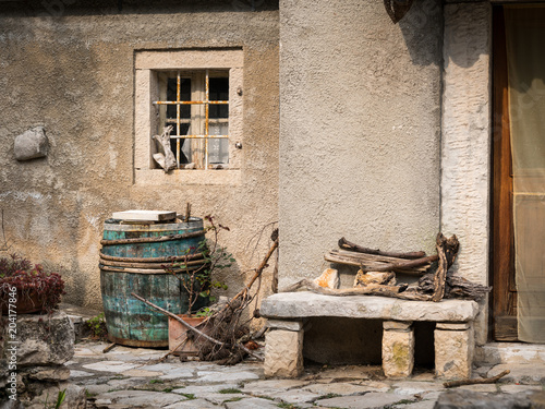 Wine barrel and stone bench in front of an old house in Valun