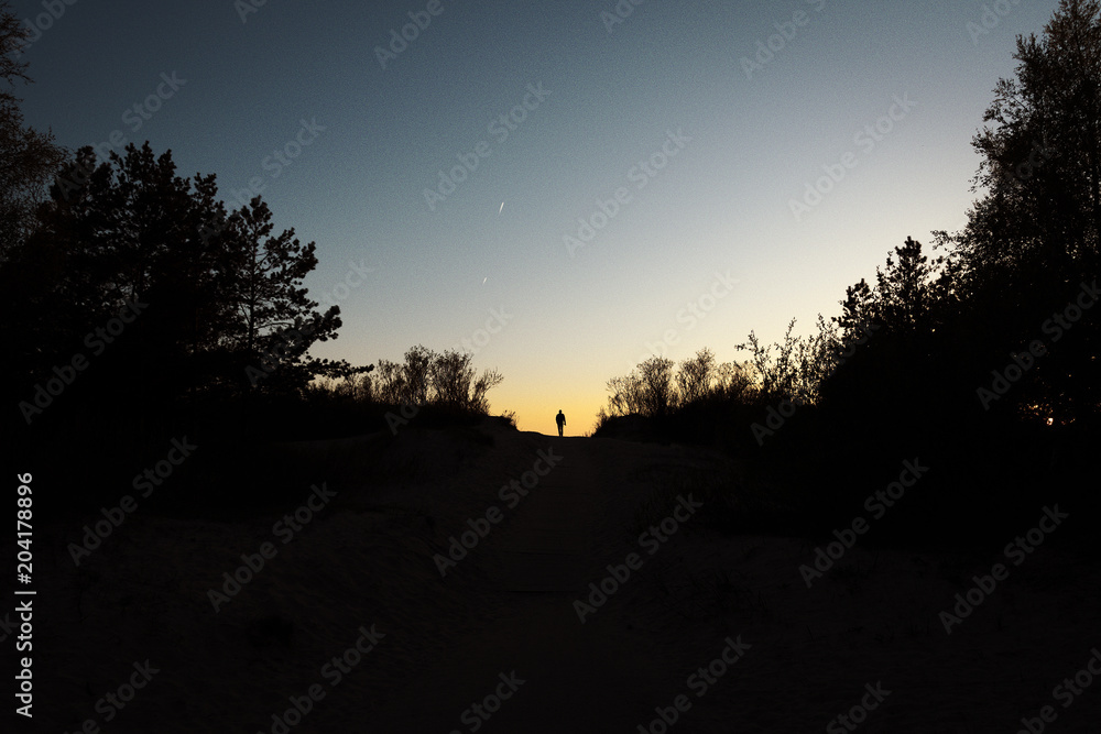 Silhouette on Baltic dunes in evening.