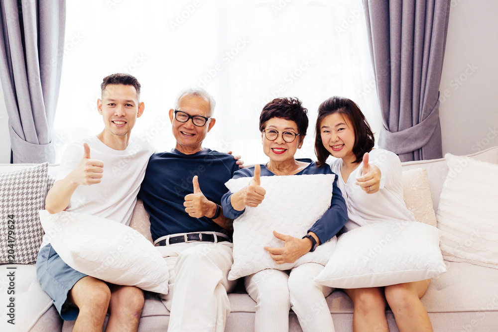 Asian family with adult children and senior parents giving thumbs up and relaxing on a sofa at home together. Happy family time together Asian family with adult children and senior parents giving thumbs up and relaxing on a sofa at home together. Happy family time together