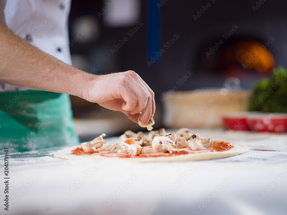 chef putting fresh mushrooms on pizza dough