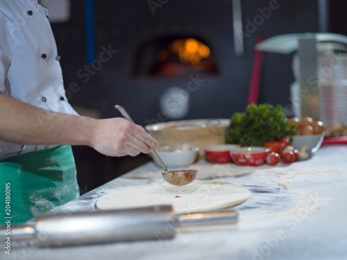 chef putting cut sausage or ham on pizza dough