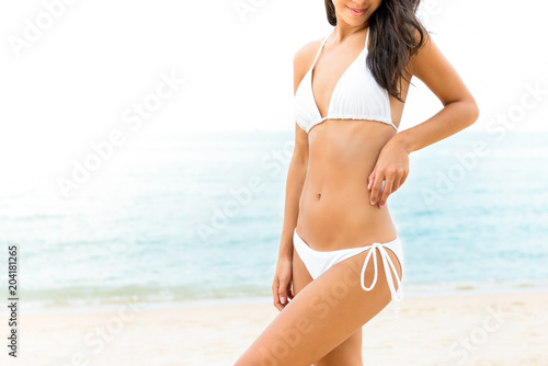 Beautiful shape woman in white bikini swimsuit posing at the beach