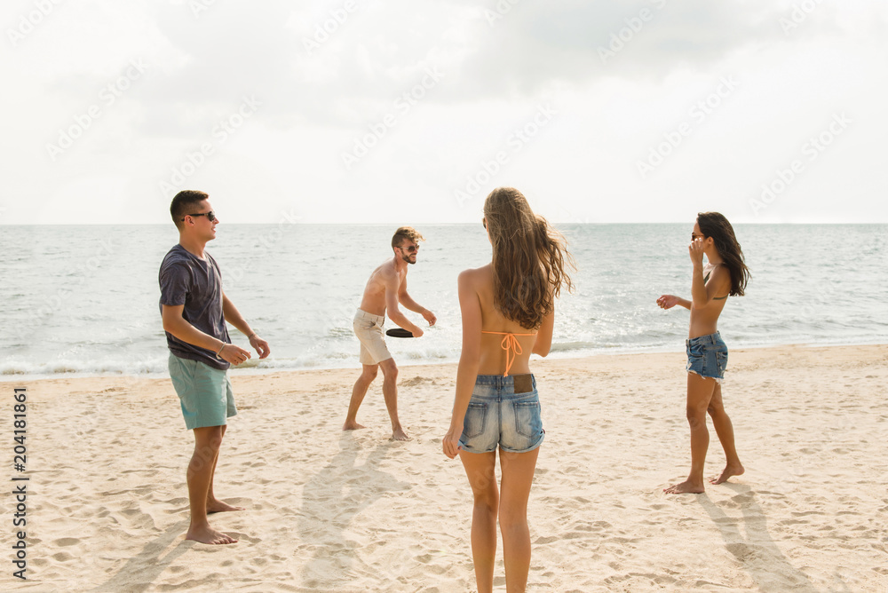Group of friends playing at the beach on summer holidays