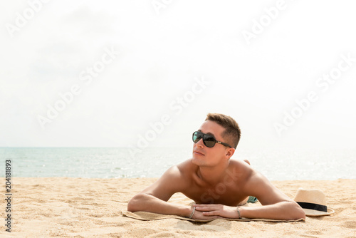Young handsome man lying at the beach on summer vacations