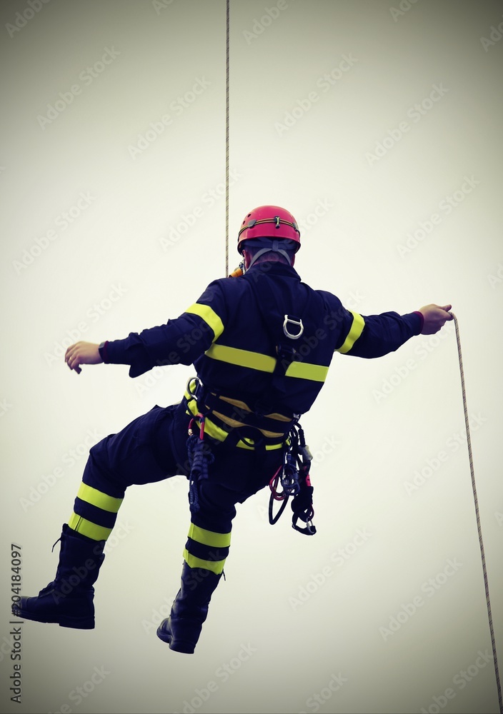Fototapeta premium fireman hanging from a cord suspended with vintage effect