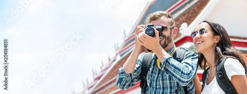 Interracial tourist couple taking photos during summer holiday trip in Bangkok Thailand