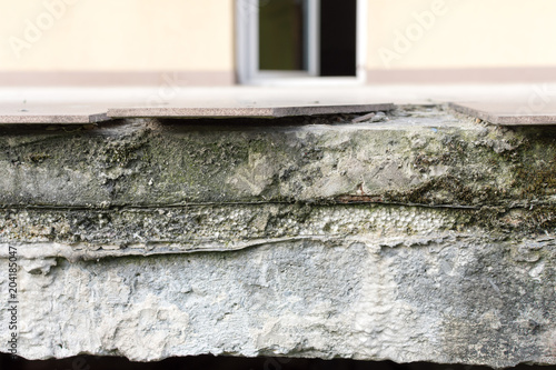 Damaged wet front of the balcony and broken ceramic tile with layers due to improper construction