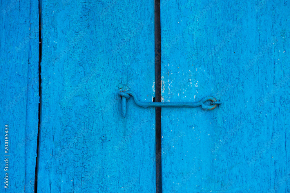The old blue door is closed on the hook. Background and texture of an old wooden door The old blue door is closed on the hook. Background and texture of an old wooden door