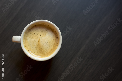 Cup of coffee on a wooden background. Kind from above.