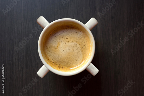 Cup of coffee with four pens by close-up on a wooden background. Top view