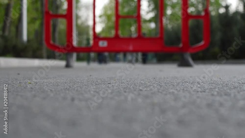 Low angle view of the hipster in blue canvas shoes riding a blue plastic penny skateboard in the city park. Concept of the youth culture, freedom, independence, street culture, modern vision of life.