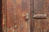 Old wooden door dark red color and old iron lock (fragment)