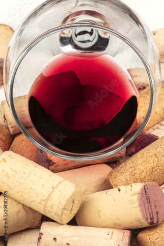 A closeup photo of a glass of red wine with wine corks