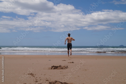 Man on beach running to the sea