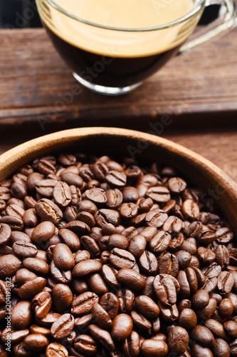 Close up of cup of coffee and coffee bean in wooden bowl