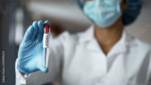 Scientist holding ebola vaccine liquid in test tube, biochemistry experiment photo