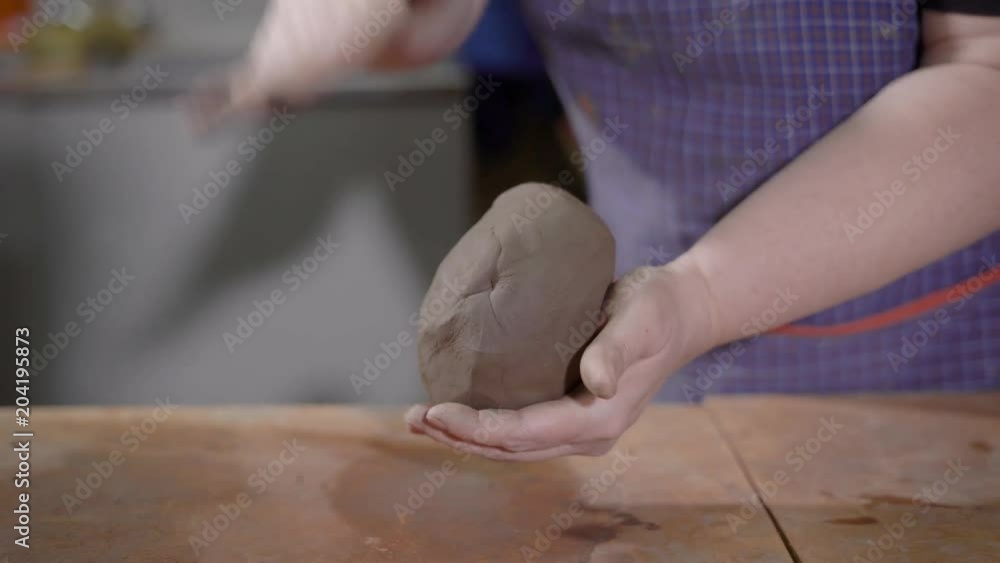 female hands are kneading and beating clay in art pottery workshop, shaping ball for making ceramic goods female hands are kneading and beating clay in art pottery workshop, shaping ball for making ceramic goods