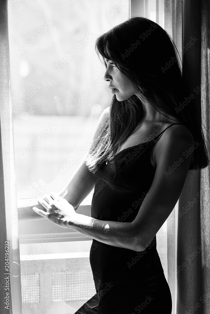 woman looking out window black and white
