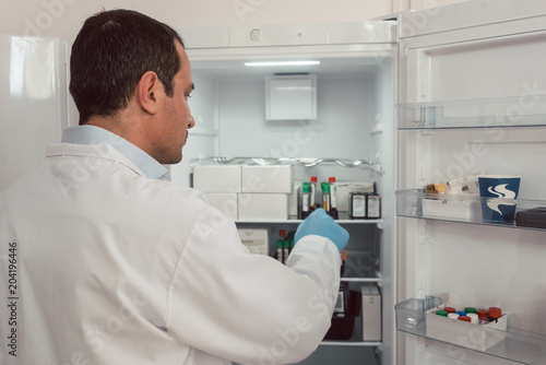 Lab technician storing blood samples in fridge for later use