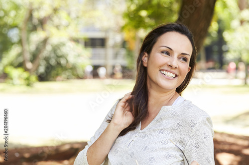 Beautiful woman smiling in park, looking away