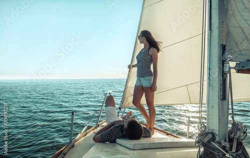 Romantic couple in love on sail boat at sunset under sunlight on