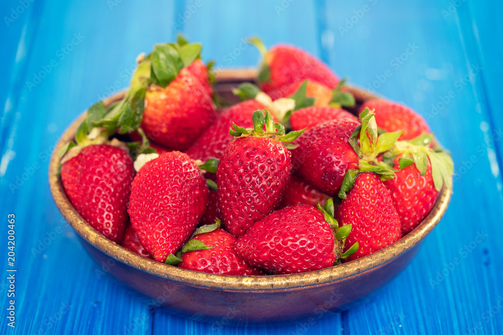 strawberries in dish on blue wooden background strawberries in dish on blue wooden background