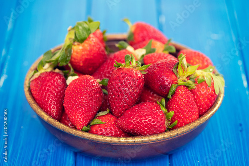 strawberries in dish on blue wooden background