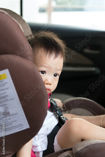 Portrait of cute Asian toddler boy sitting in car seat.