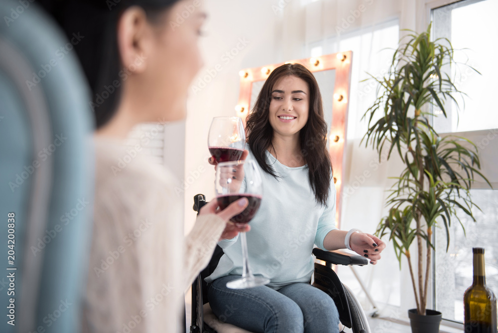 Lets celebrate. Charming handicapped woman drinking wine and talking to friend Lets celebrate. Charming handicapped woman drinking wine and talking to friend
