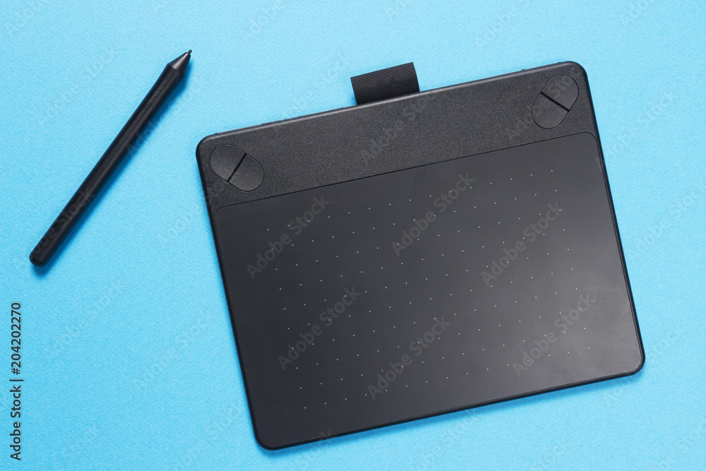 Black graphic tablet with pen on blue background. The designer tool